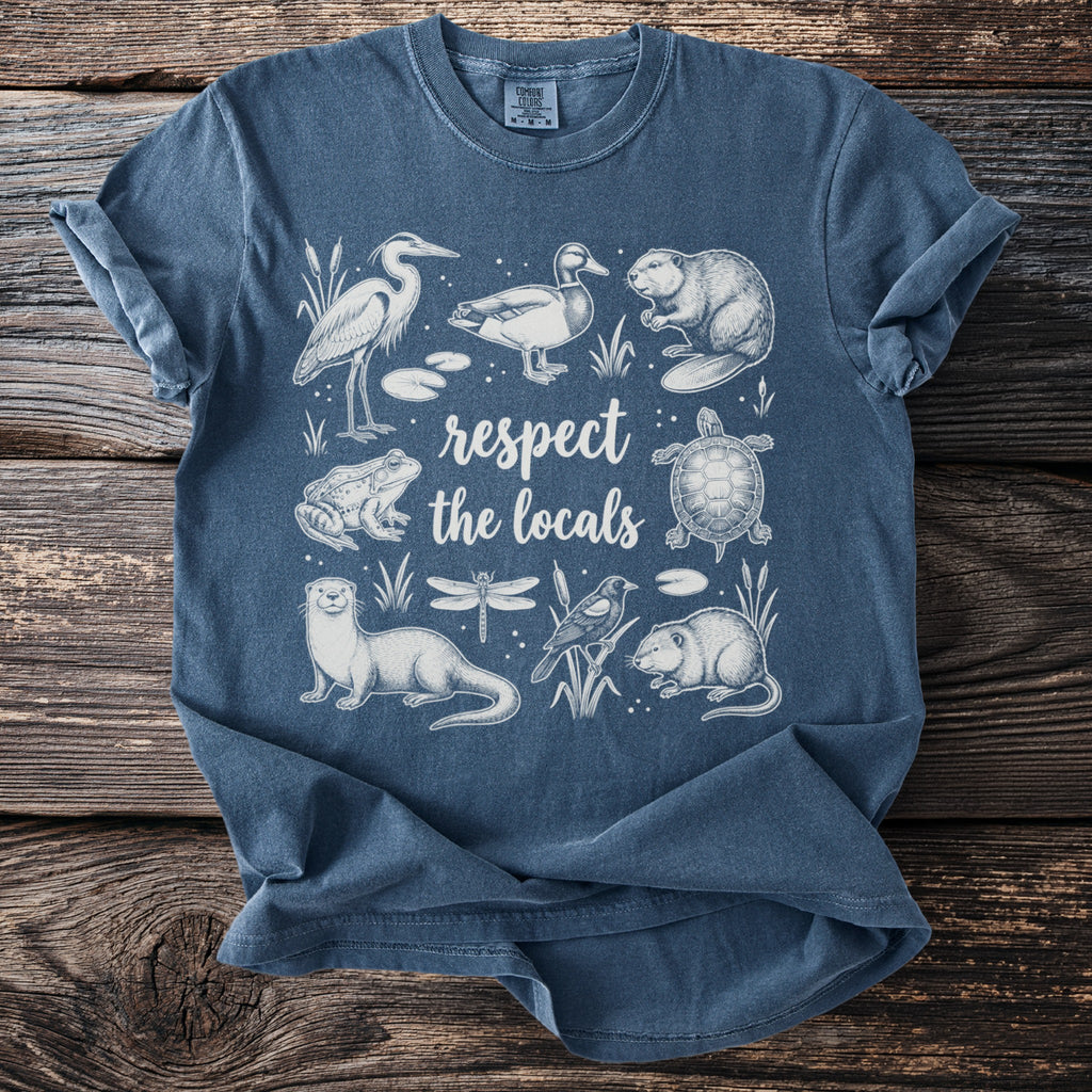 Blue t-shirt with white line art of marsh animals and the words "respect the locals."