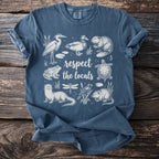 Blue t-shirt with white line art of marsh animals and the words "respect the locals."