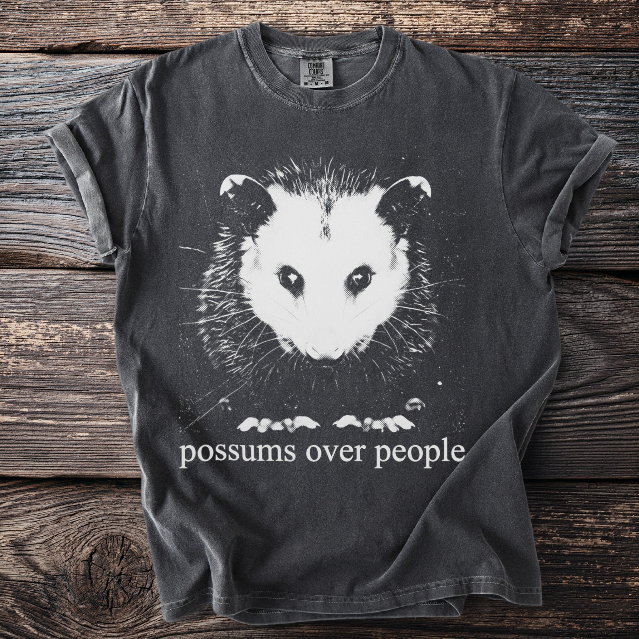 Charcoal t-shirt with a white graphic of an opossum and text "possums over people".