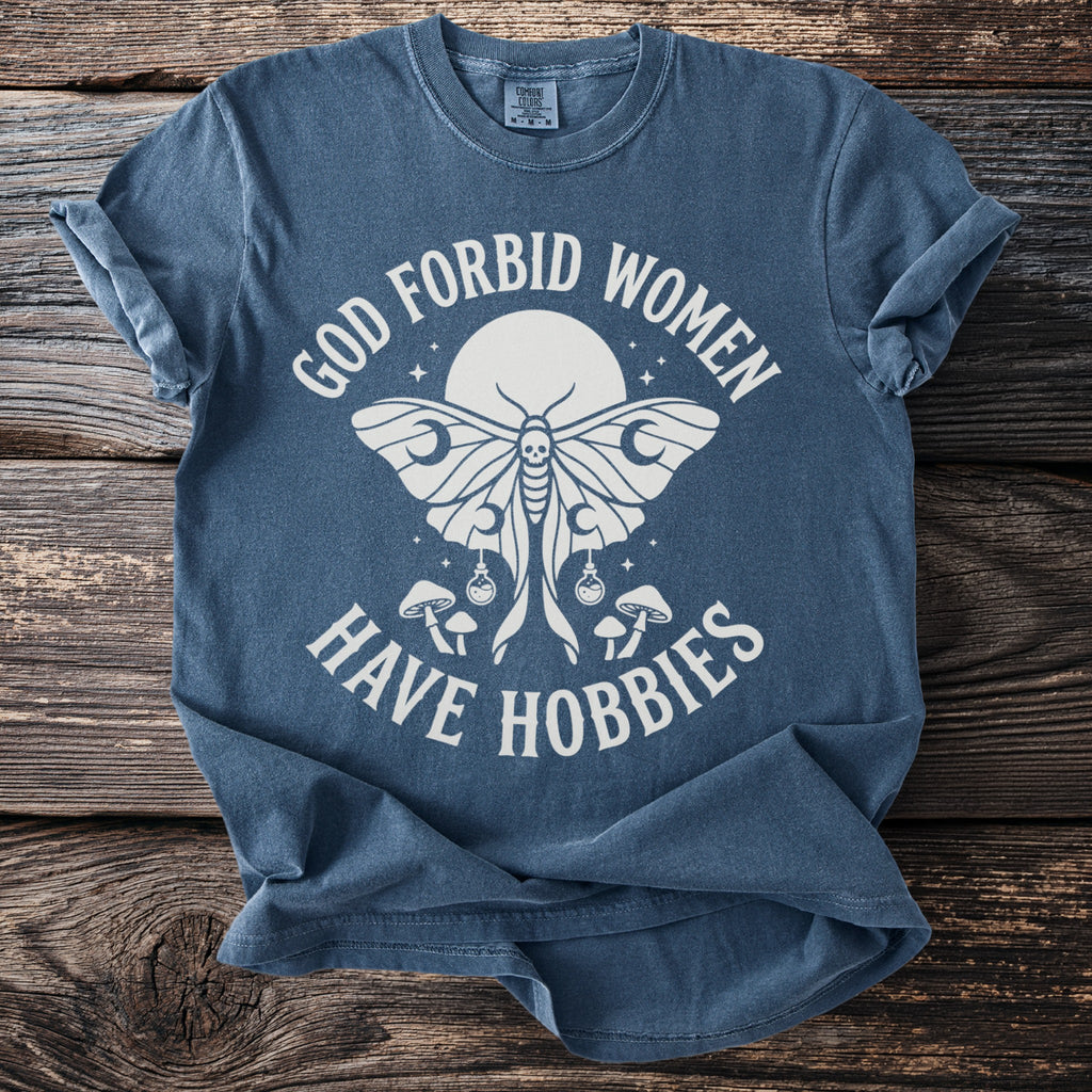 Blue t-shirt with moth, mushrooms, and text: "God Forbid Women Have Hobbies."