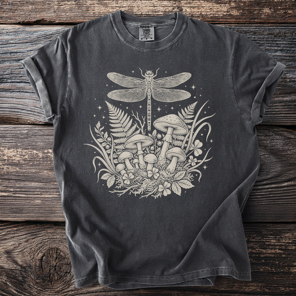 T-shirt with a cream-colored print of a dragonfly, mushrooms, ferns, and clover.