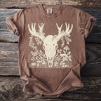 Brown t-shirt with cream line art of deer skull, antlers, foliage, and mushrooms.