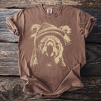 Brown t-shirt with a beige graphic of a koala wearing a beanie on a wooden background.