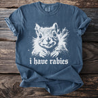 Blue t-shirt with white graphic of a squirrel and text "i have rabies".