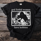 Black t-shirt with "god forbid women have hobbies" text and an illustration of a person with butterflies and skulls.