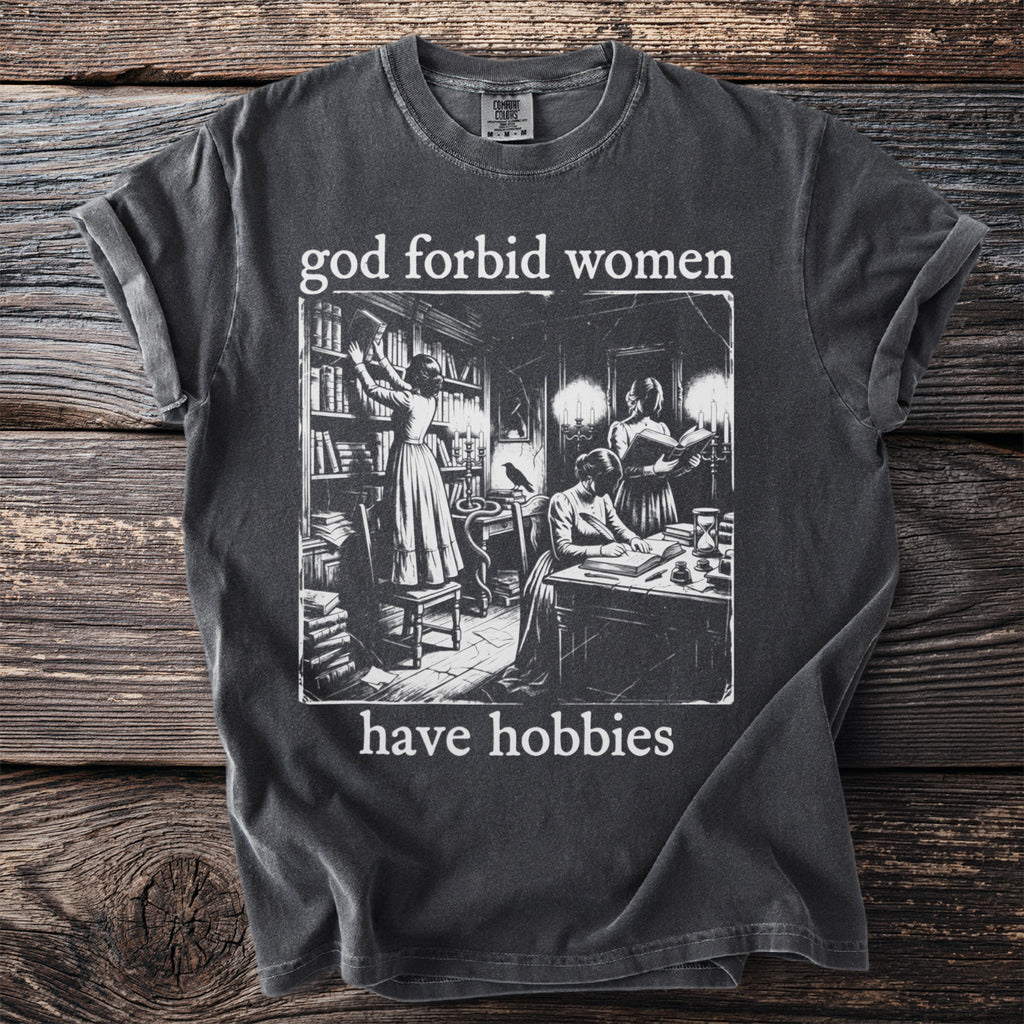 Dark grey t-shirt with "god forbid women have hobbies" and vintage library illustration.