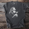 Graphic t-shirt with Bigfoot blowing dandelion seeds on a dark background.