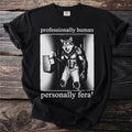 Black t-shirt with a werewolf clocking in, text reads "professionally human, personally feral".