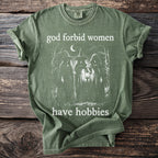 Green t-shirt with "god forbid women have hobbies" and three witches graphic.