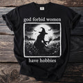 Black t-shirt with "god forbid women have hobbies" text and witch illustration.