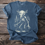 Blue t-shirt with a skeletal creature with antlers and claws in a forest.