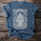 Blue t-shirt with a cream-colored graphic of a woman surrounded by moon phases and foliage.