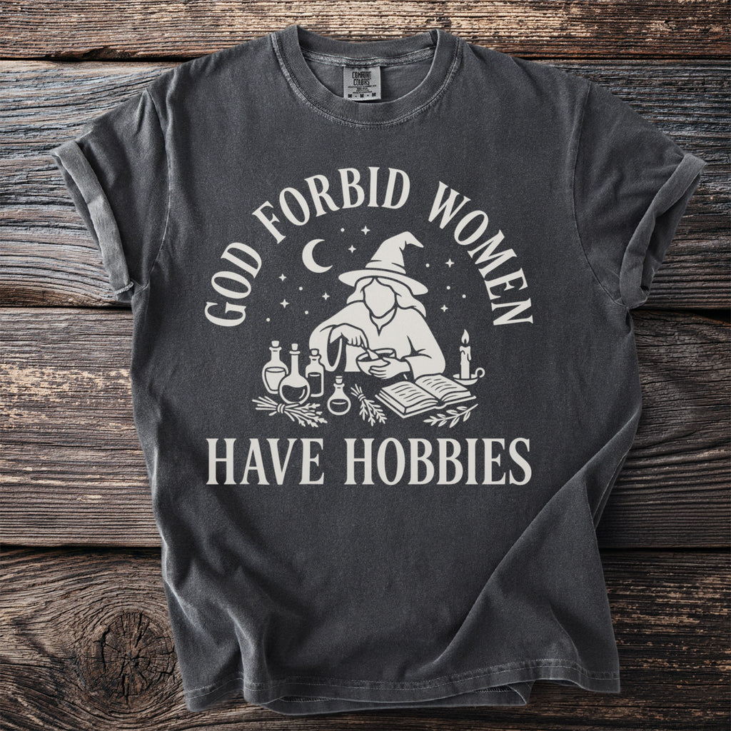 Dark gray t-shirt with "GOD FORBID WOMEN HAVE HOBBIES" text and witch graphic.