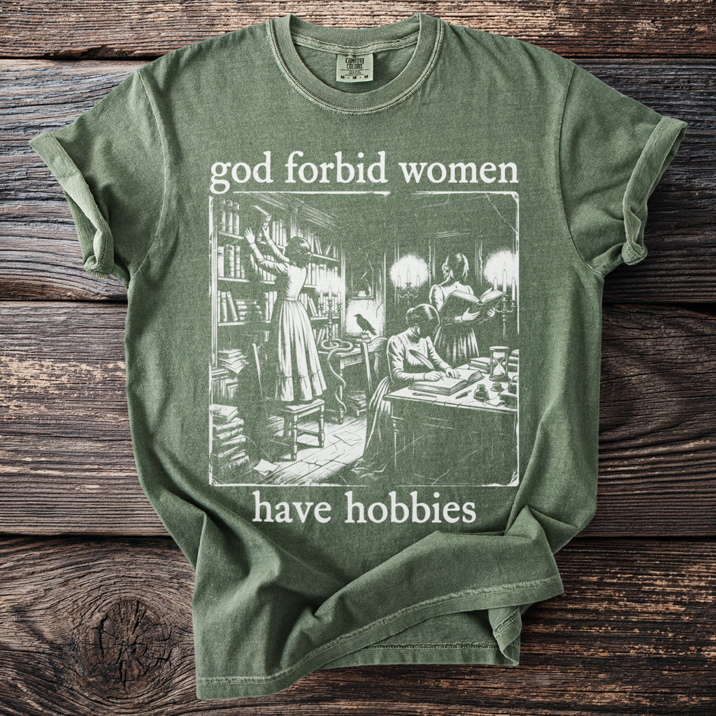 Green t-shirt with "god forbid women have hobbies" text and vintage library illustration.