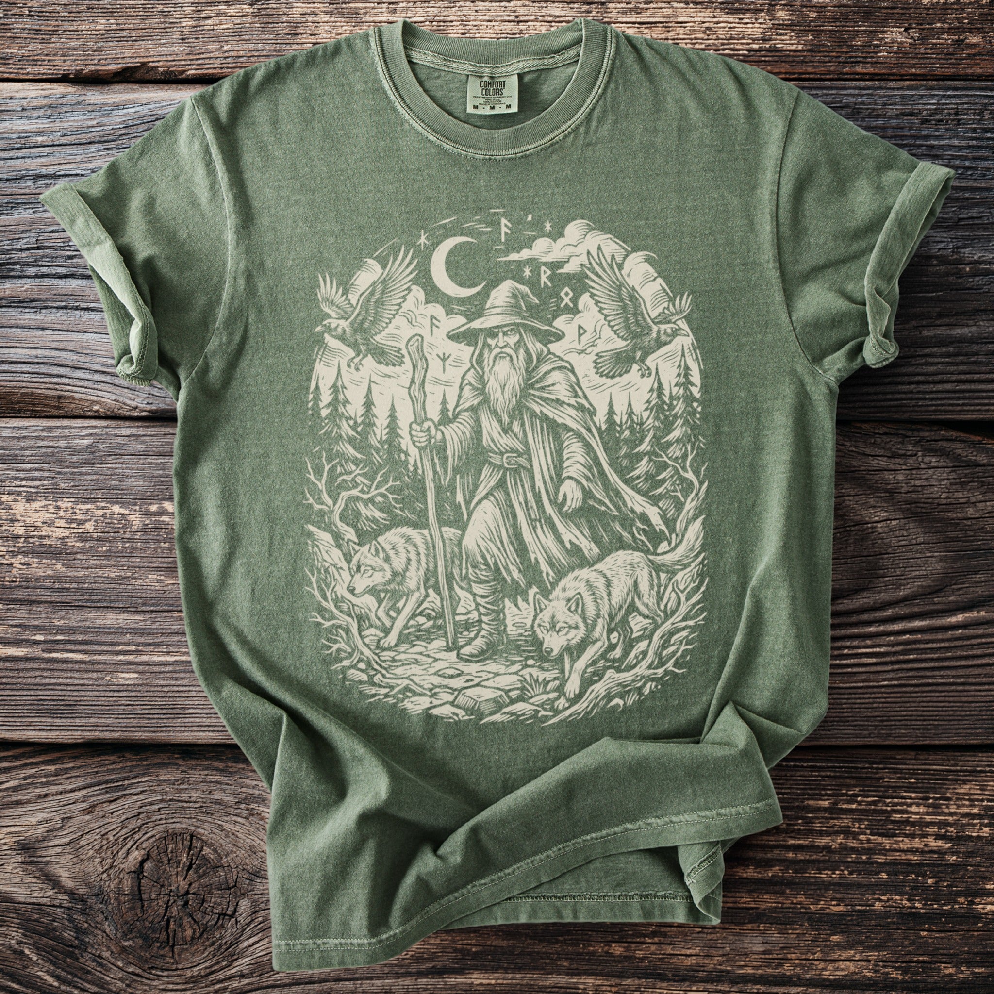 Green t-shirt with a cream graphic of a wizard, two wolves, two ravens, and runes.