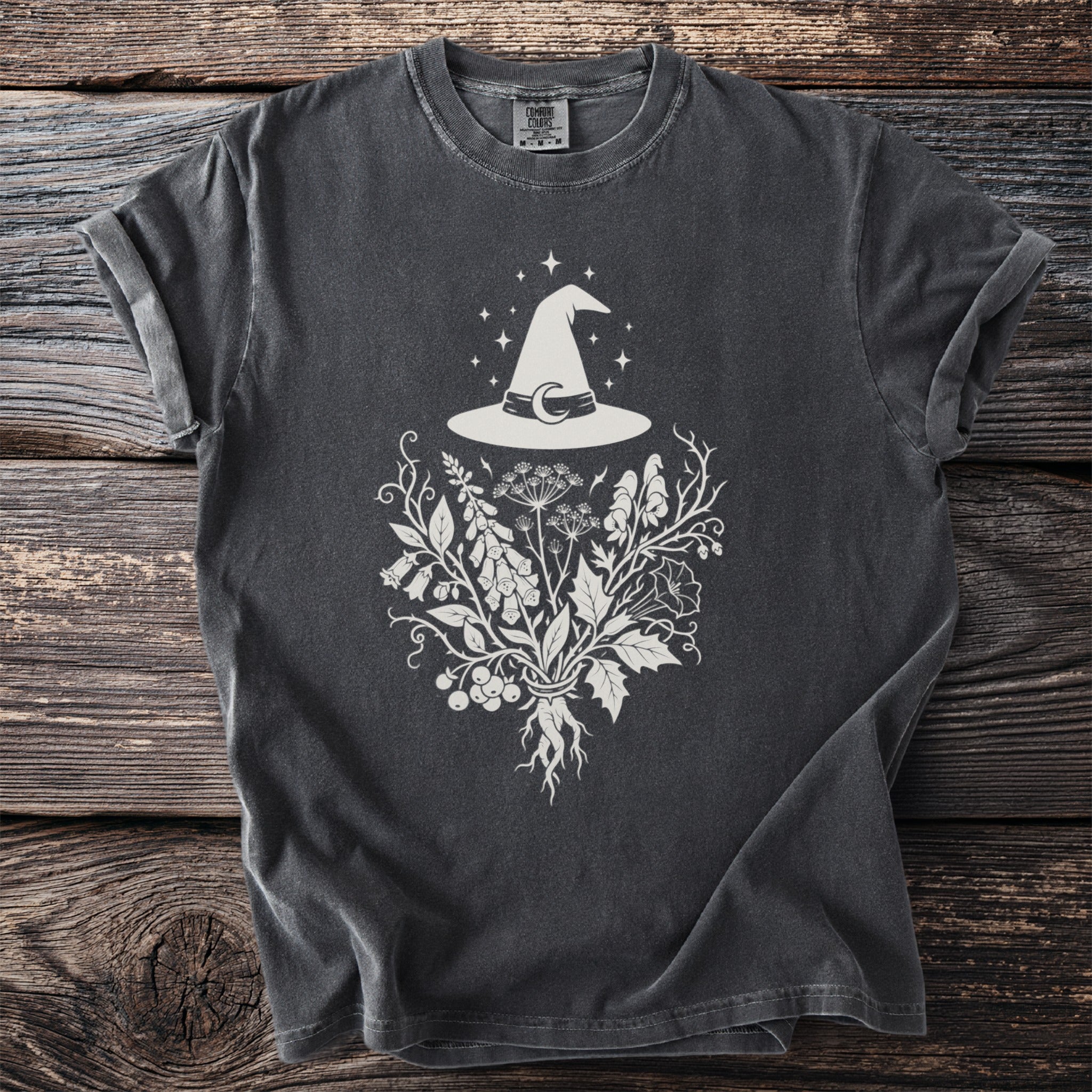 Dark gray t-shirt with witch hat, crescent moon, and botanical illustration design.