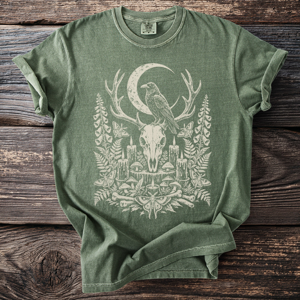 Green t-shirt featuring a crow on deer antlers, moon, candles, mushrooms, and moths.