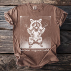 Brown t-shirt with a graphic of a raccoon and text "become ungovernable".