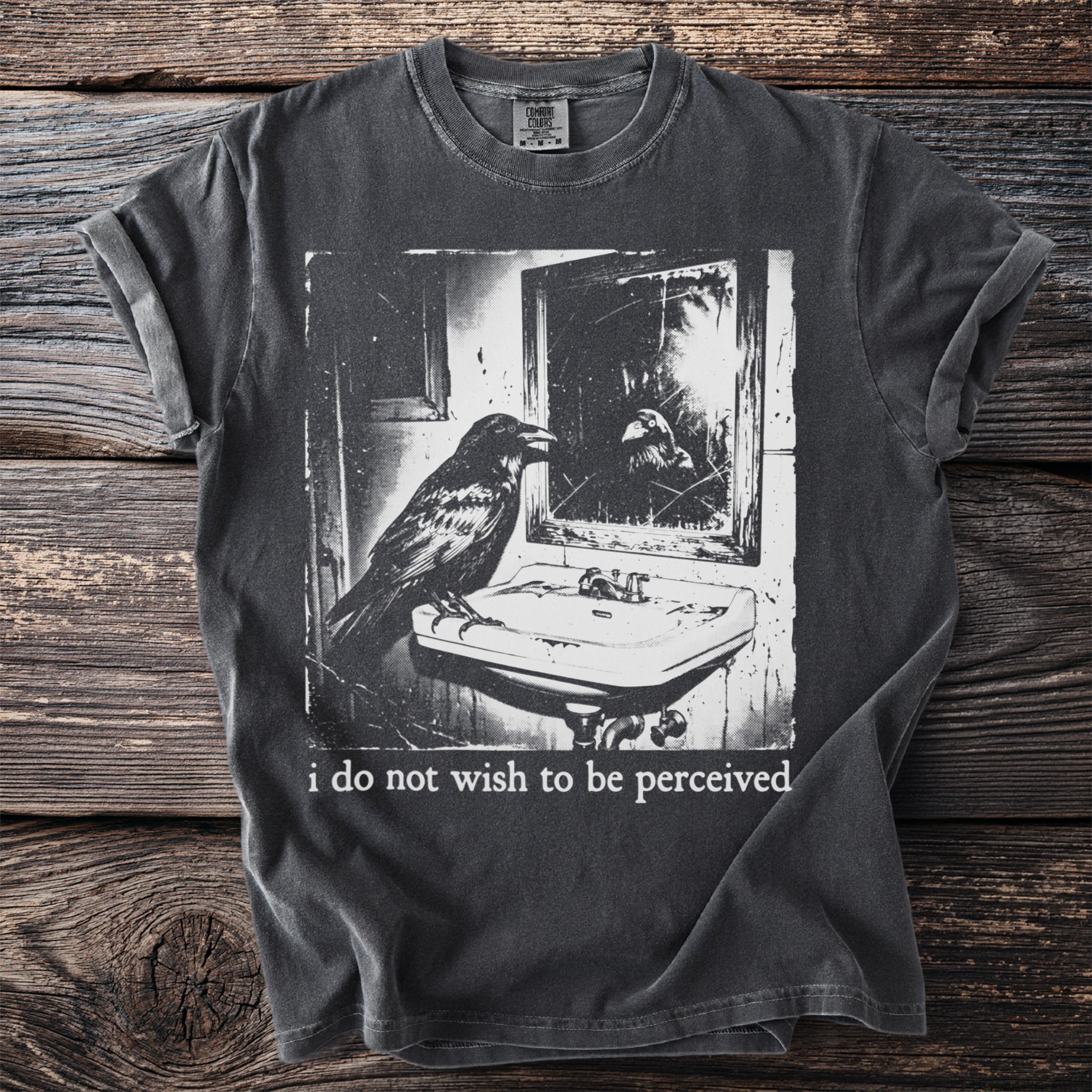 Dark t-shirt with print of a raven looking in a mirror and the text "i do not wish to be perceived."