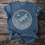Blue t-shirt with a white oval graphic of a dragonfly and moon over wildflowers.