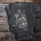 Dark t-shirt with white line art of a witch, mandrake, and black henbane under a moon.