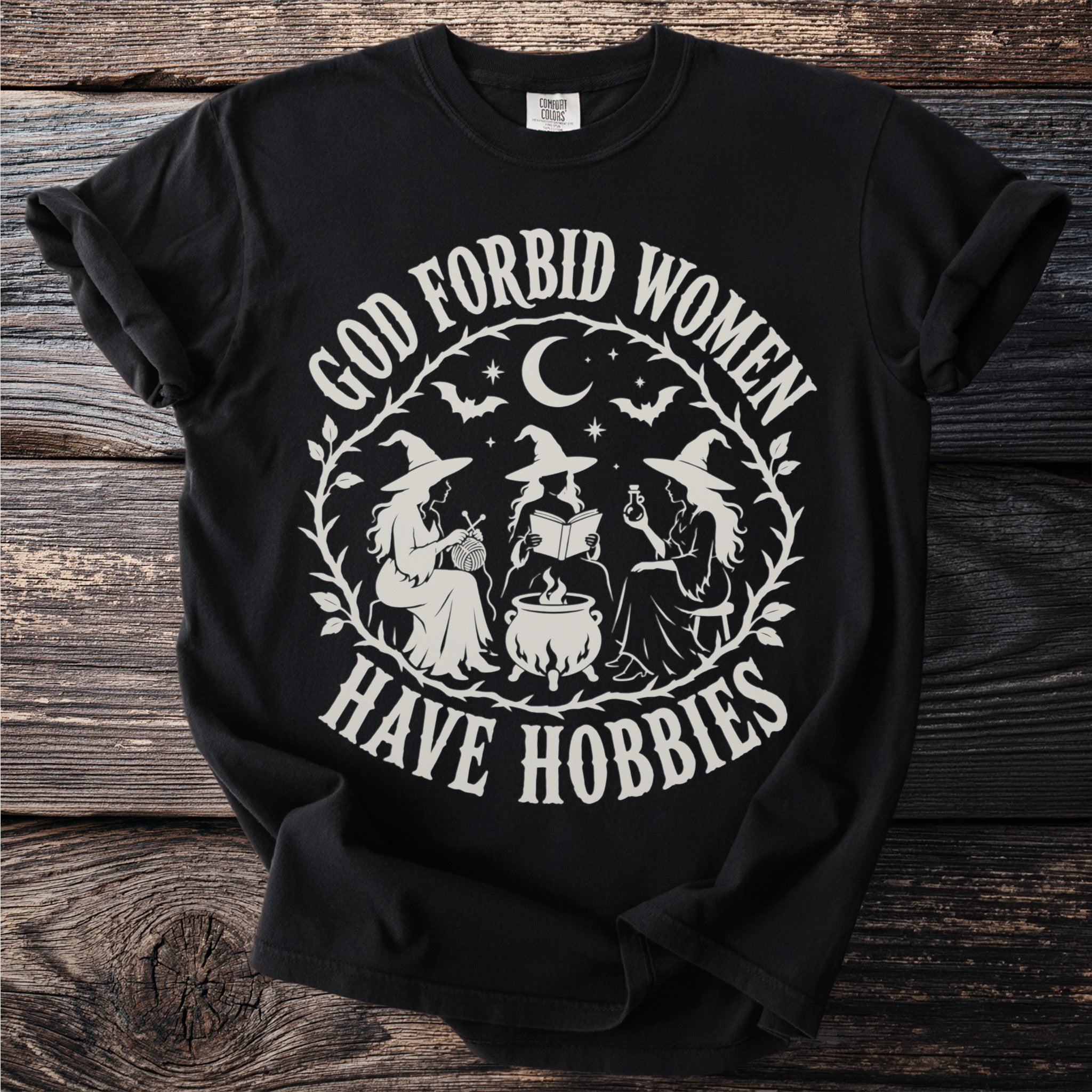 Black t-shirt with white graphic of three witches and the text "God Forbid Women Have Hobbies".