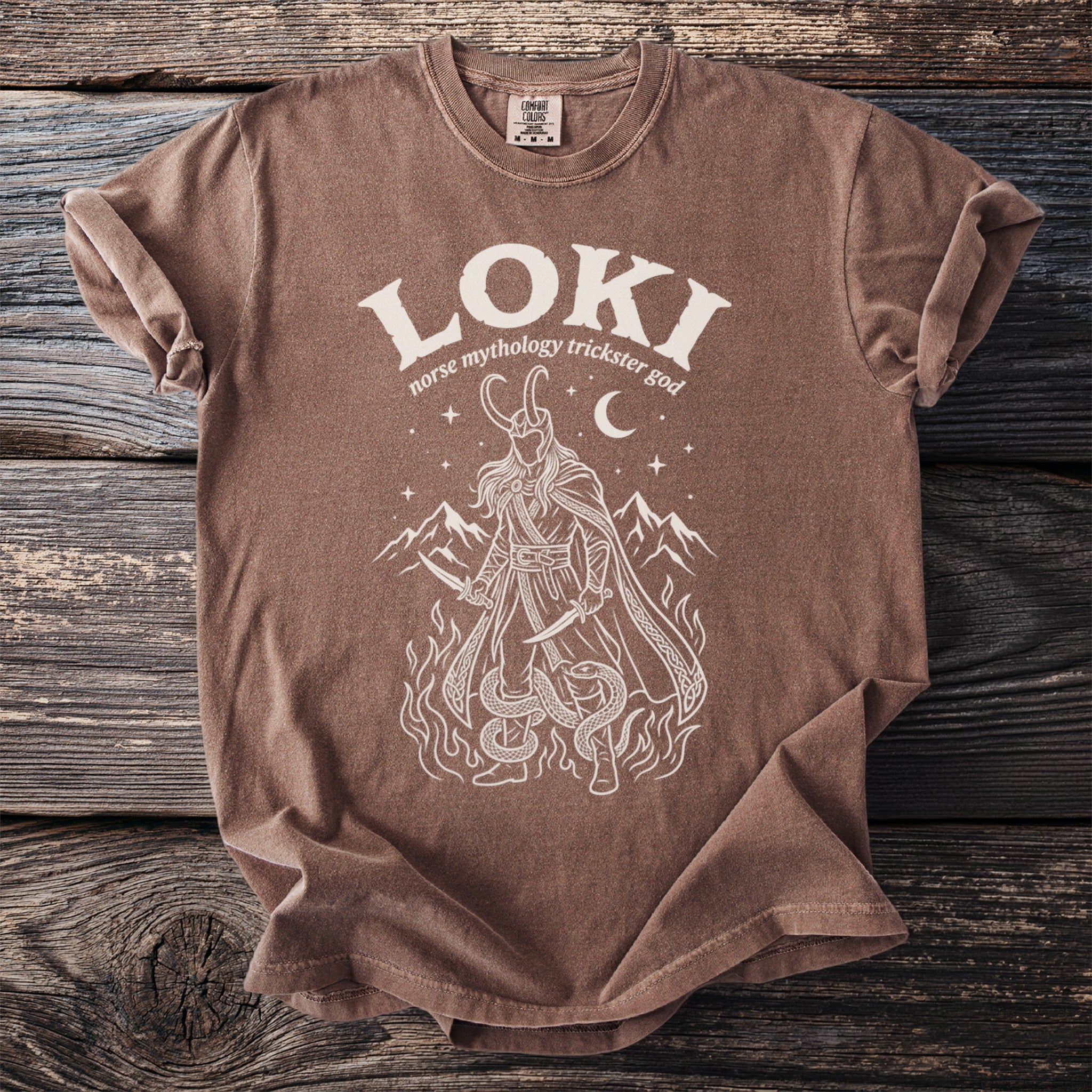 Brown t-shirt with white graphic of Loki, mountains, fire, and snakes.
