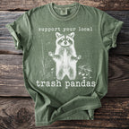 Green t-shirt with a graphic of a raccoon and text "support your local trash pandas".
