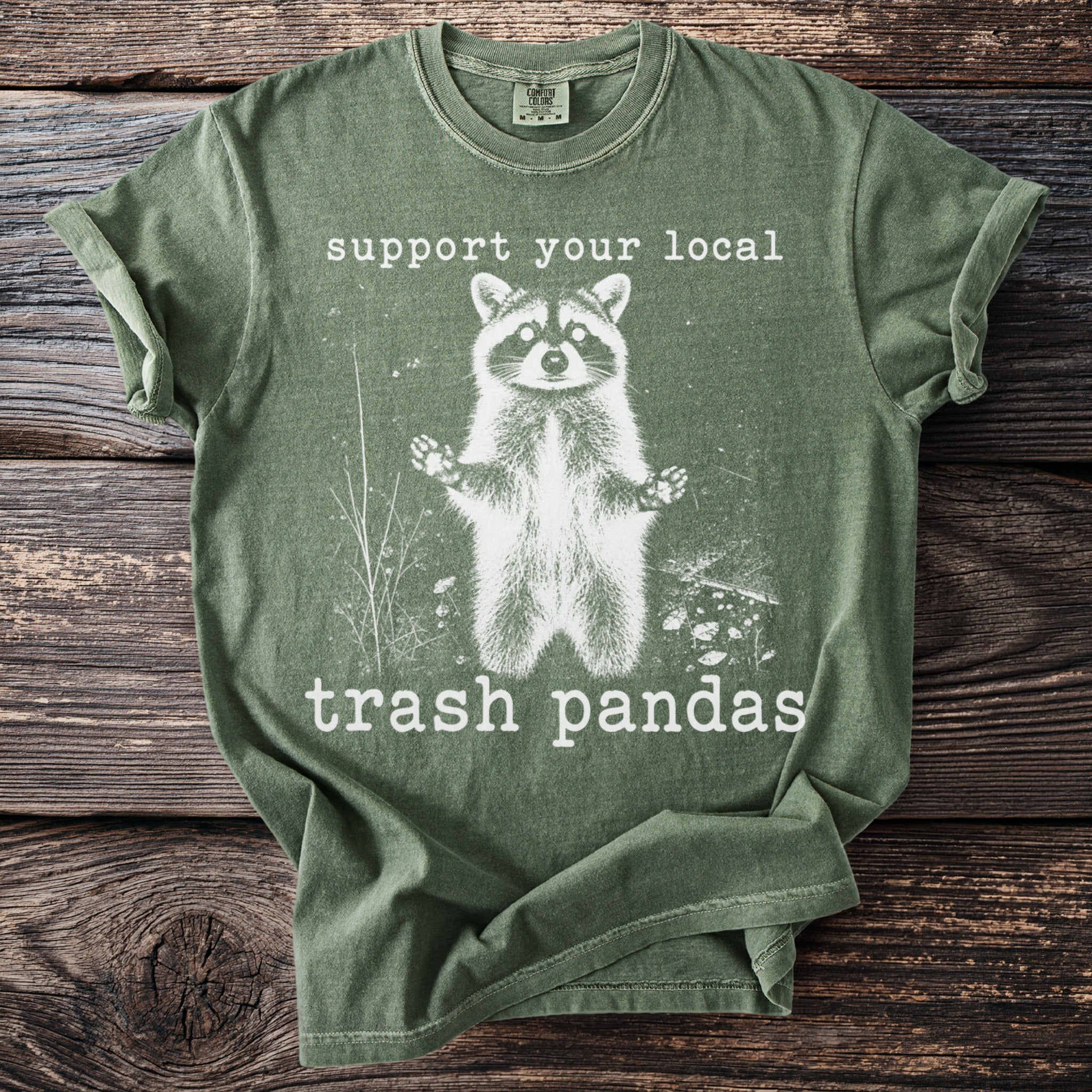 Green t-shirt with a graphic of a raccoon and text "support your local trash pandas".