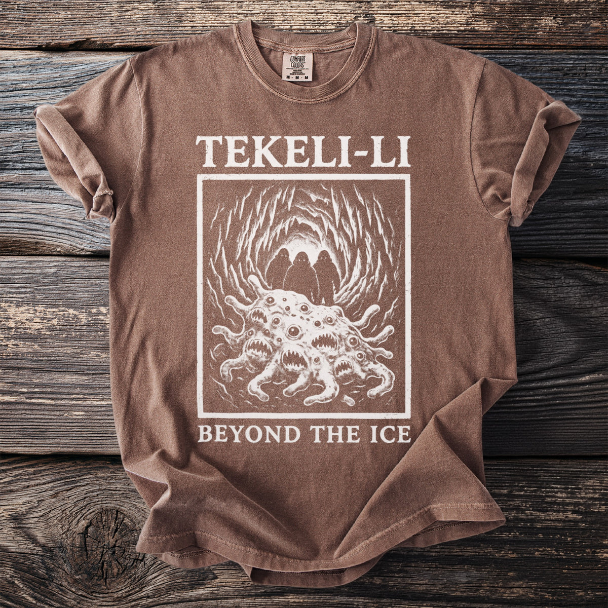 Brown t-shirt with "TEKELI-LI BEYOND THE ICE" text and horror monster graphic.
