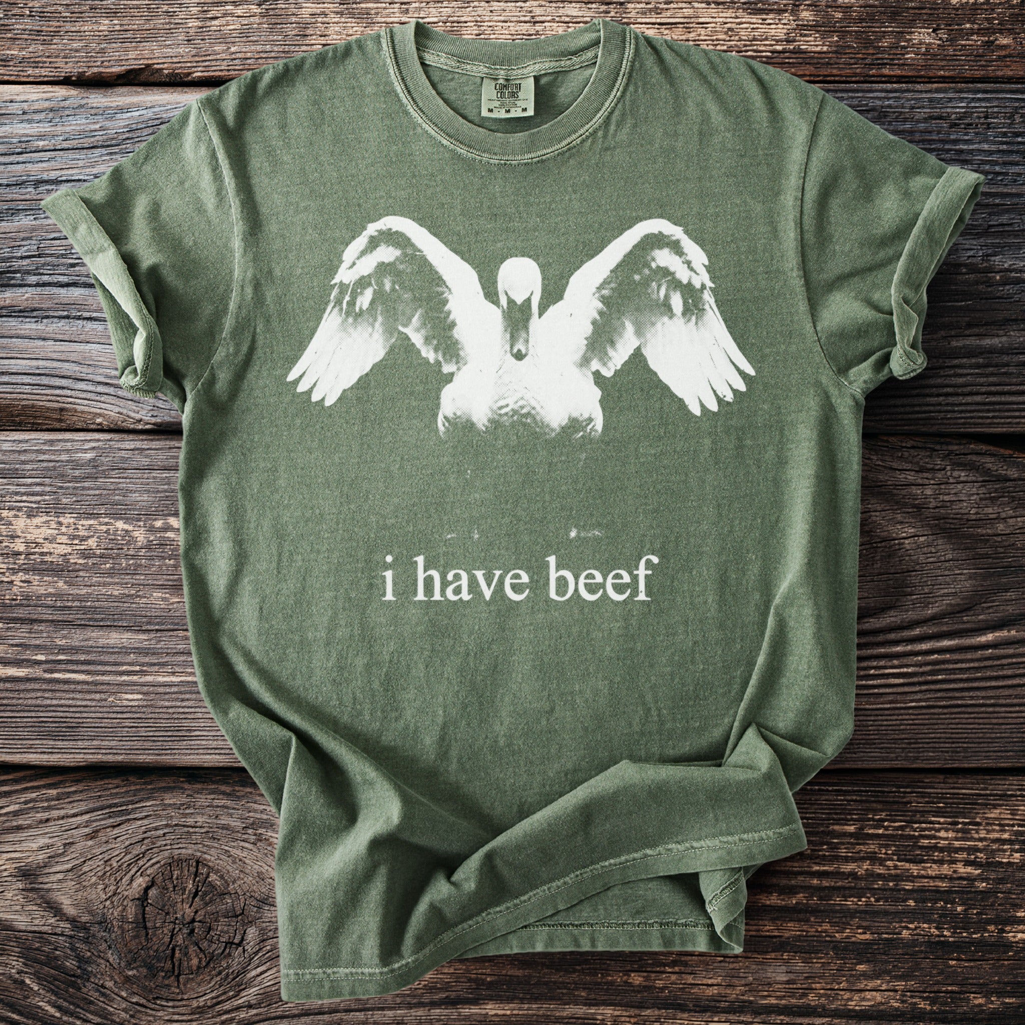 Green t-shirt with white swan graphic and "i have beef" text.