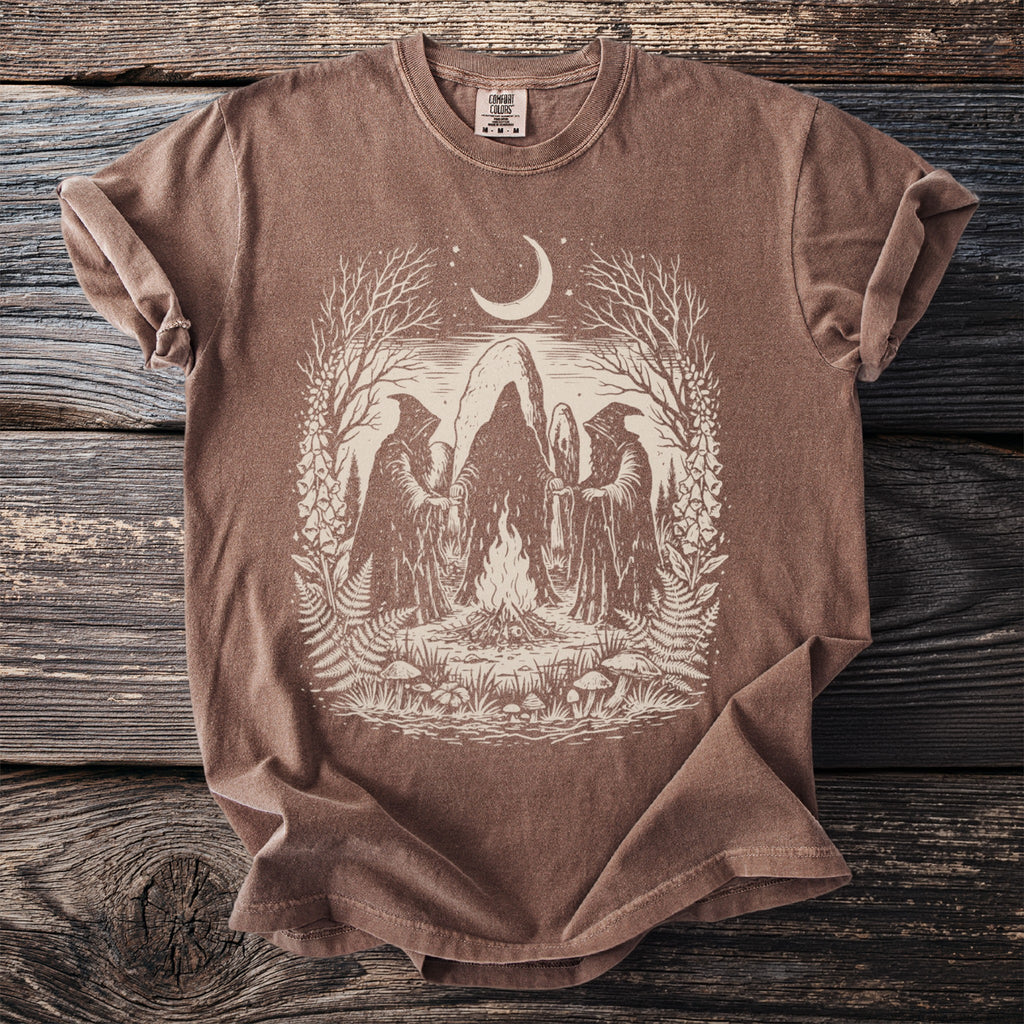Brown Comfort Colors t-shirt with a cream graphic of figures around a bonfire under a moon.