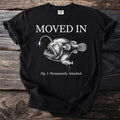 Black t-shirt with "MOVED IN" and an anglerfish illustration labeled "Fig. 1: Permanently Attached."