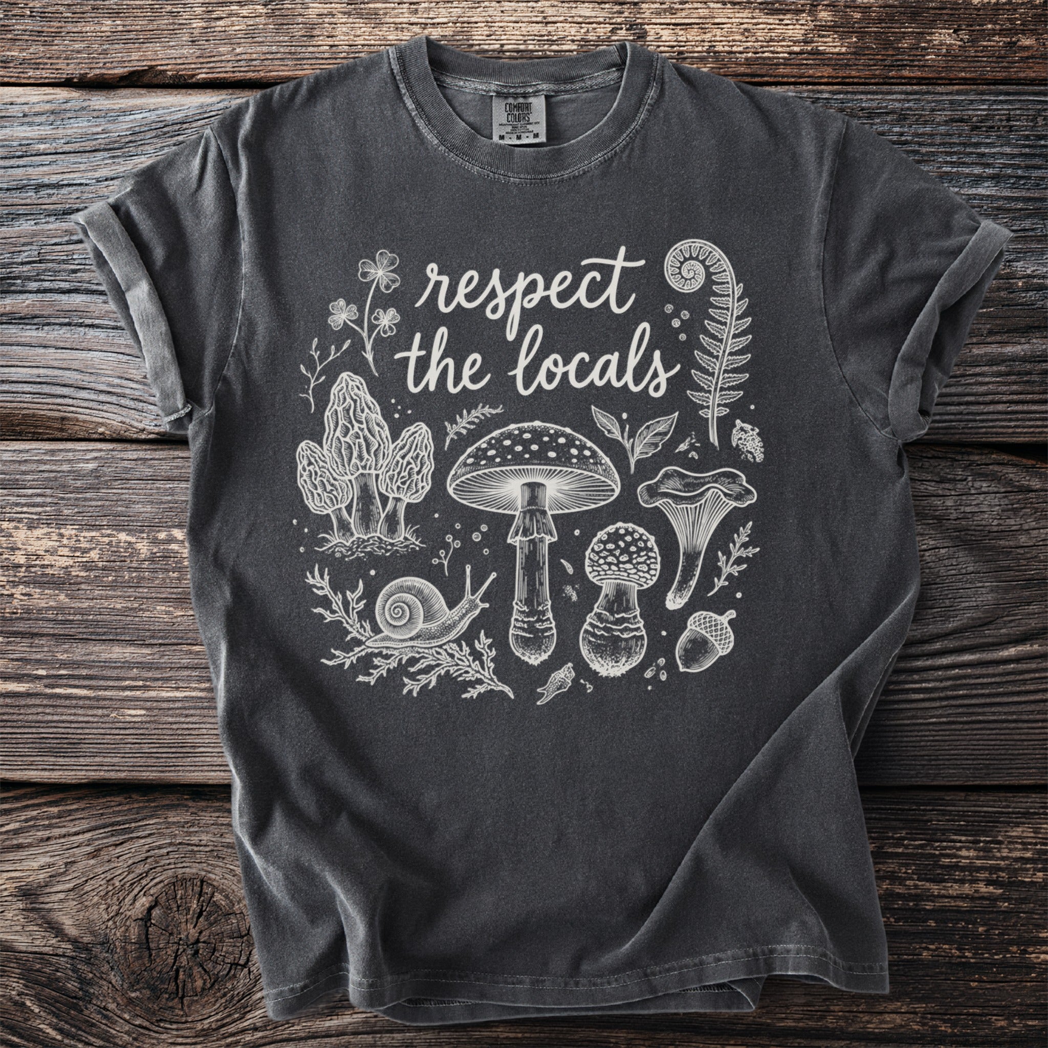 Dark gray t-shirt with white line art of mushrooms, a snail, fern, and text "respect the locals".