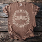 Brown t-shirt with a cream dragonfly and floral wreath graphic.