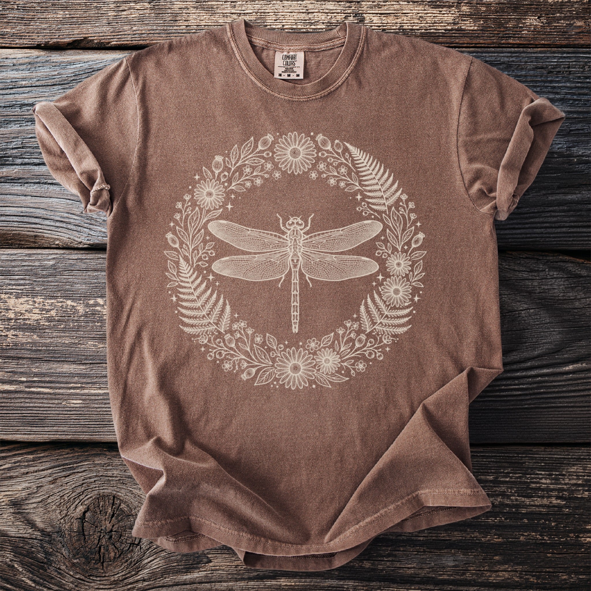 Brown t-shirt with a cream dragonfly and floral wreath graphic.