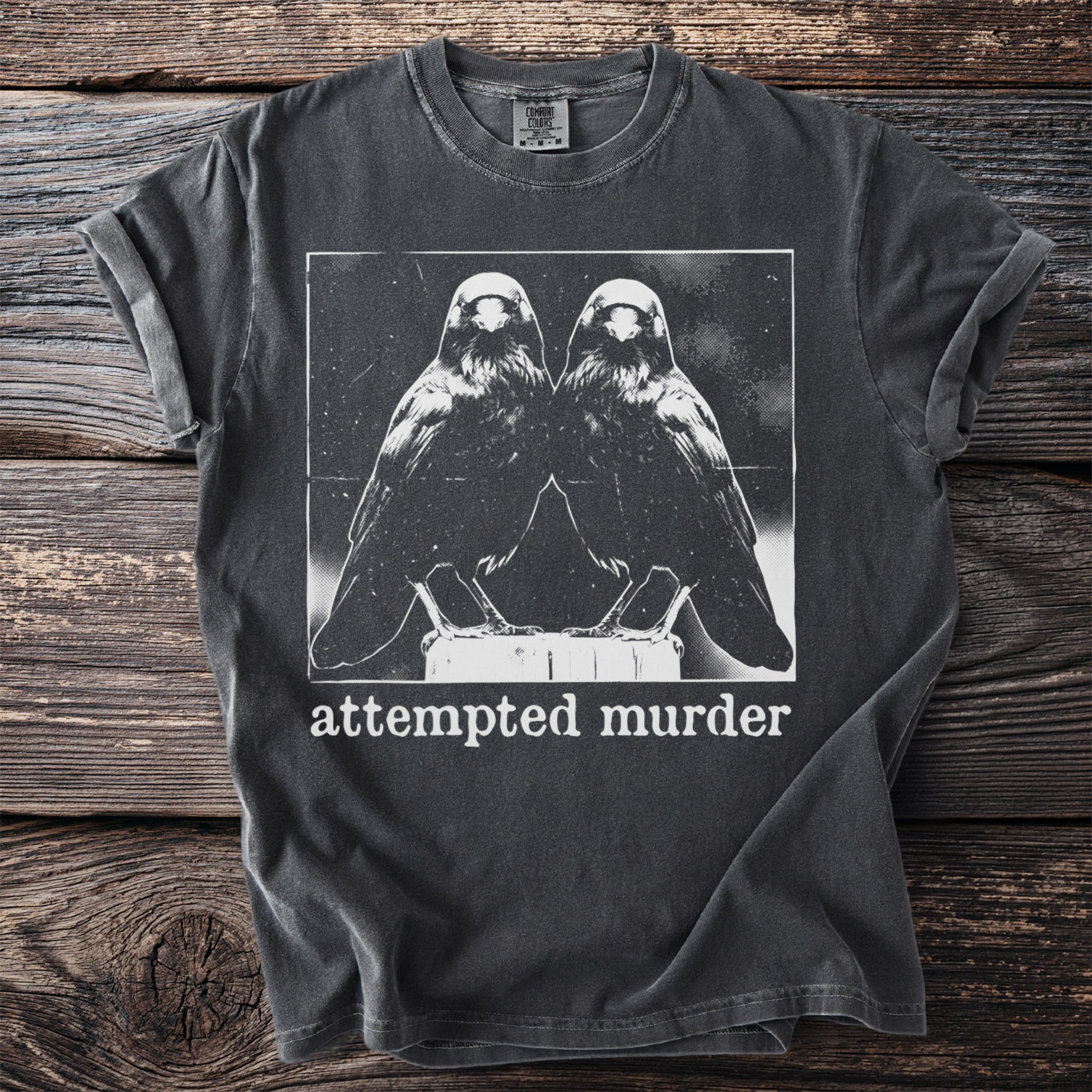 Dark charcoal t-shirt with a white graphic of two ravens and the text "attempted murder".