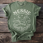 Nessie Loch Ness Scottish Cryptid graphic t-shirt on a green cotton shirt.