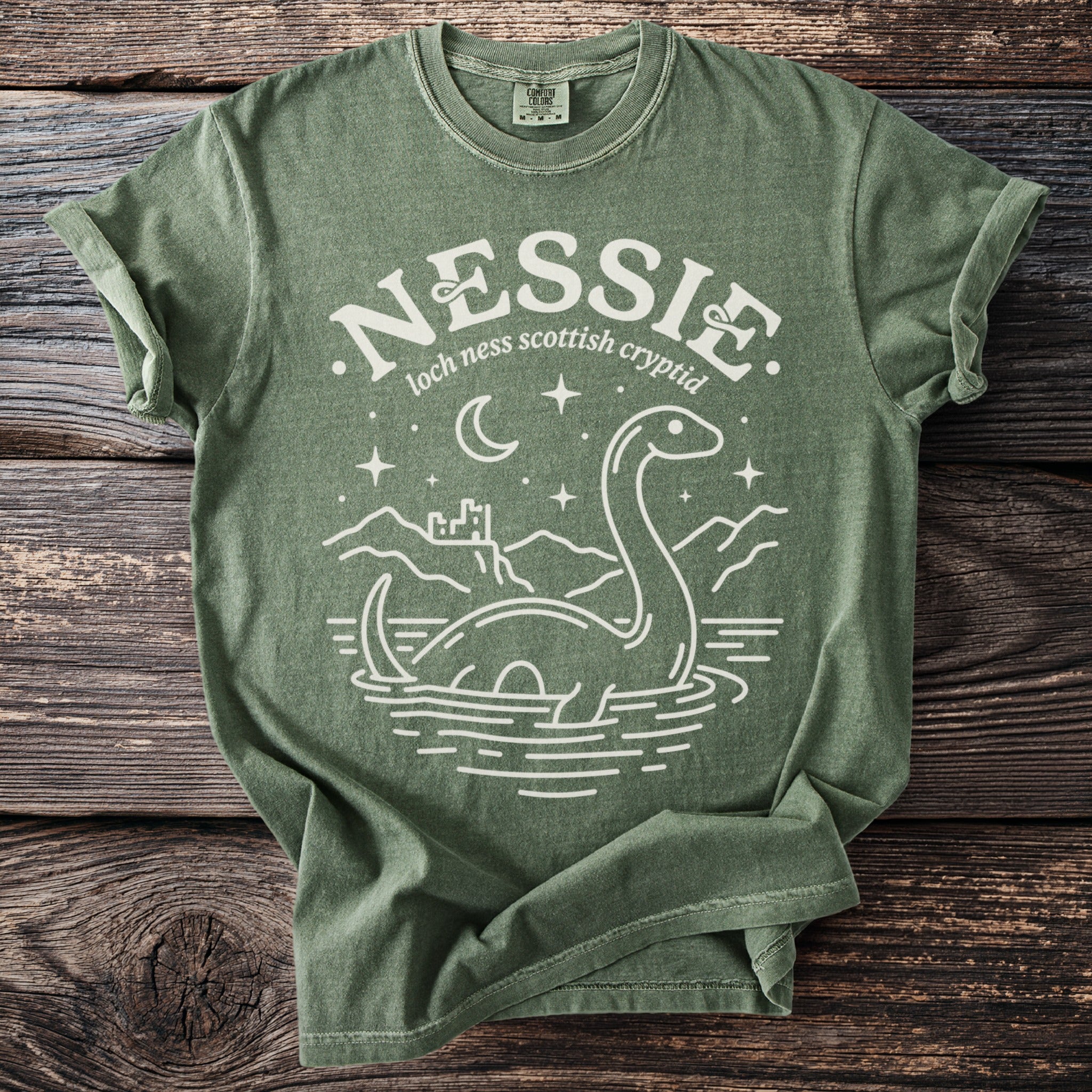 Nessie Loch Ness Scottish Cryptid graphic t-shirt on a green cotton shirt.