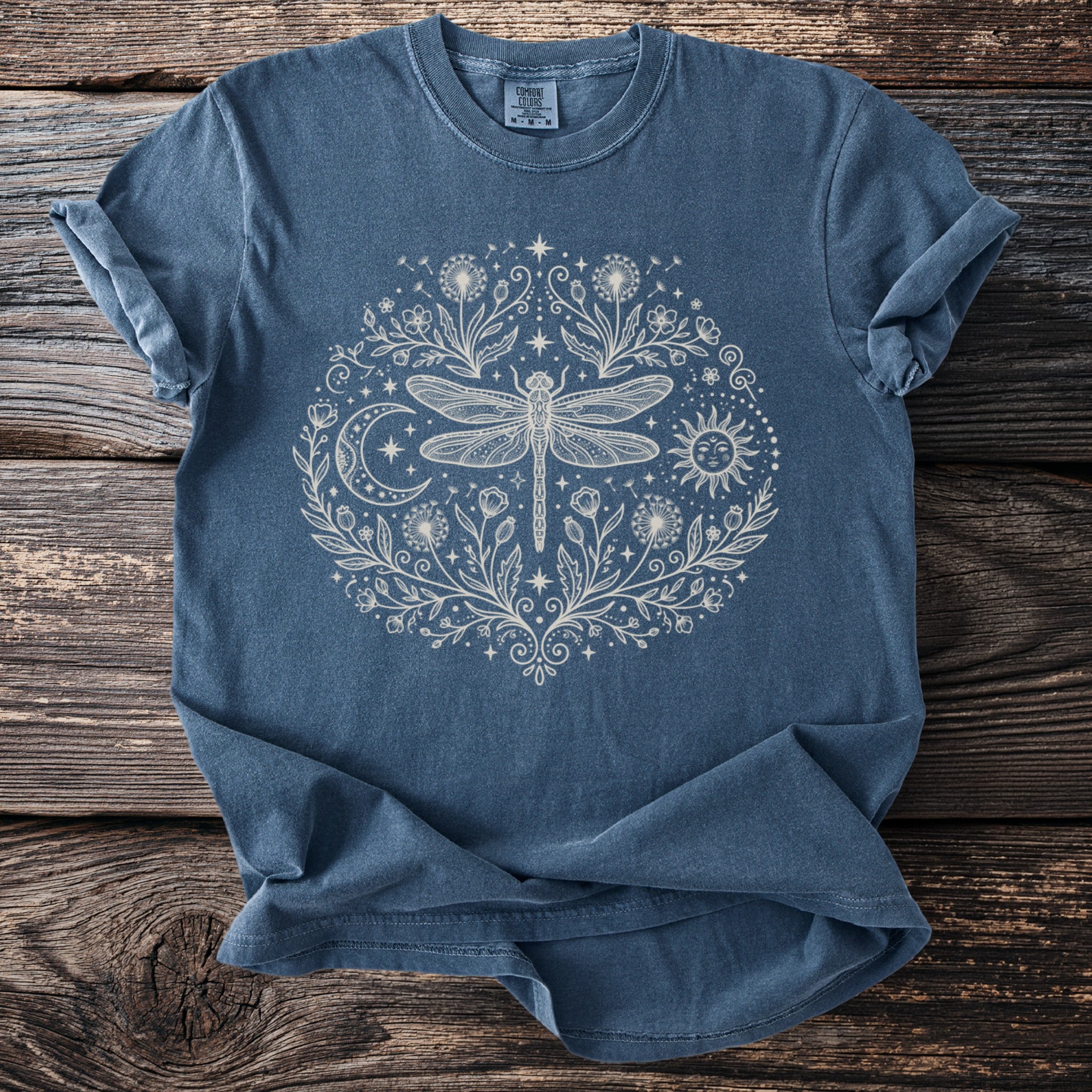Blue t-shirt with cream dragonfly, sun, moon, and floral design.