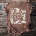 Brown t-shirt with cream drawing of wildlife and text "respect the locals".