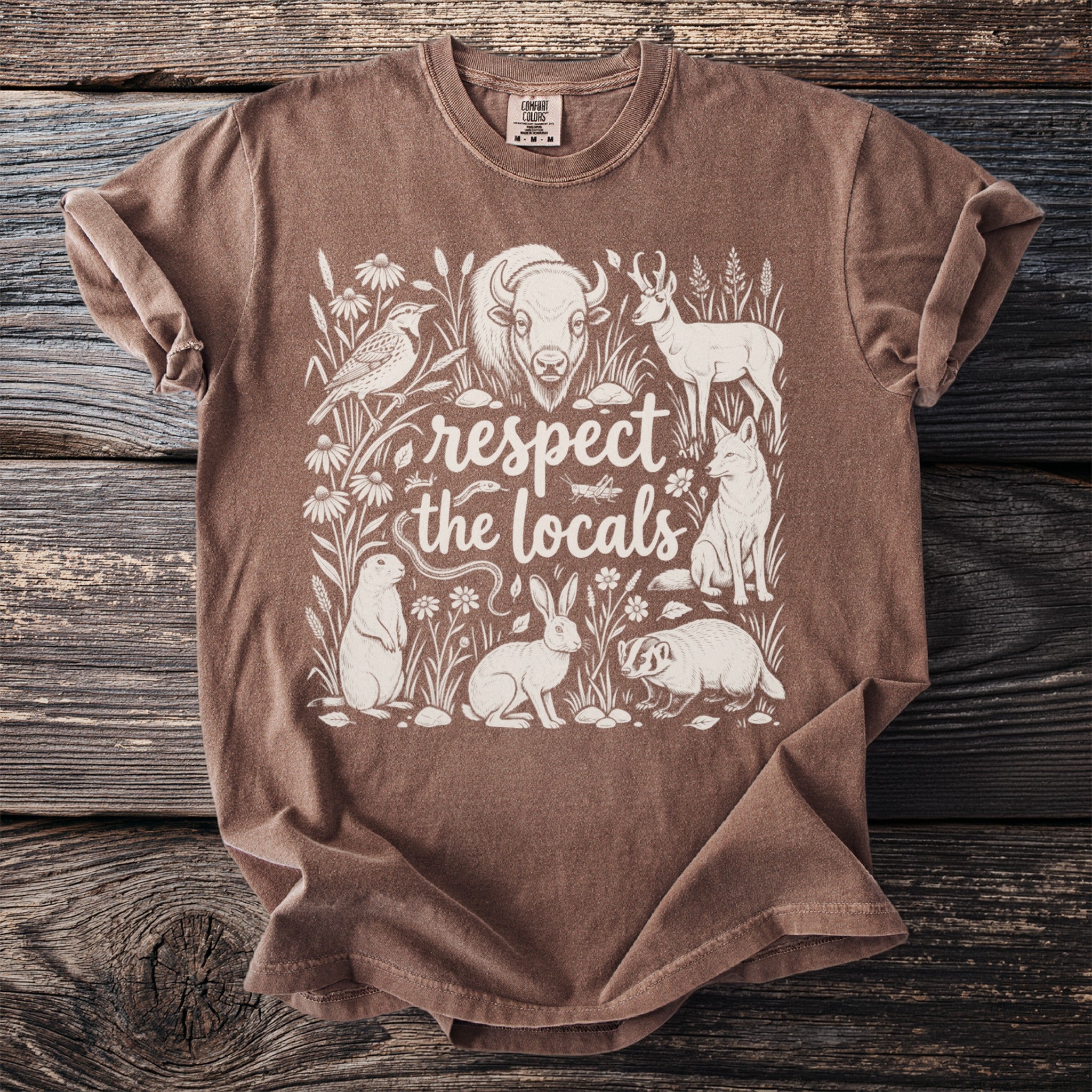 Brown t-shirt with cream drawing of wildlife and text "respect the locals".