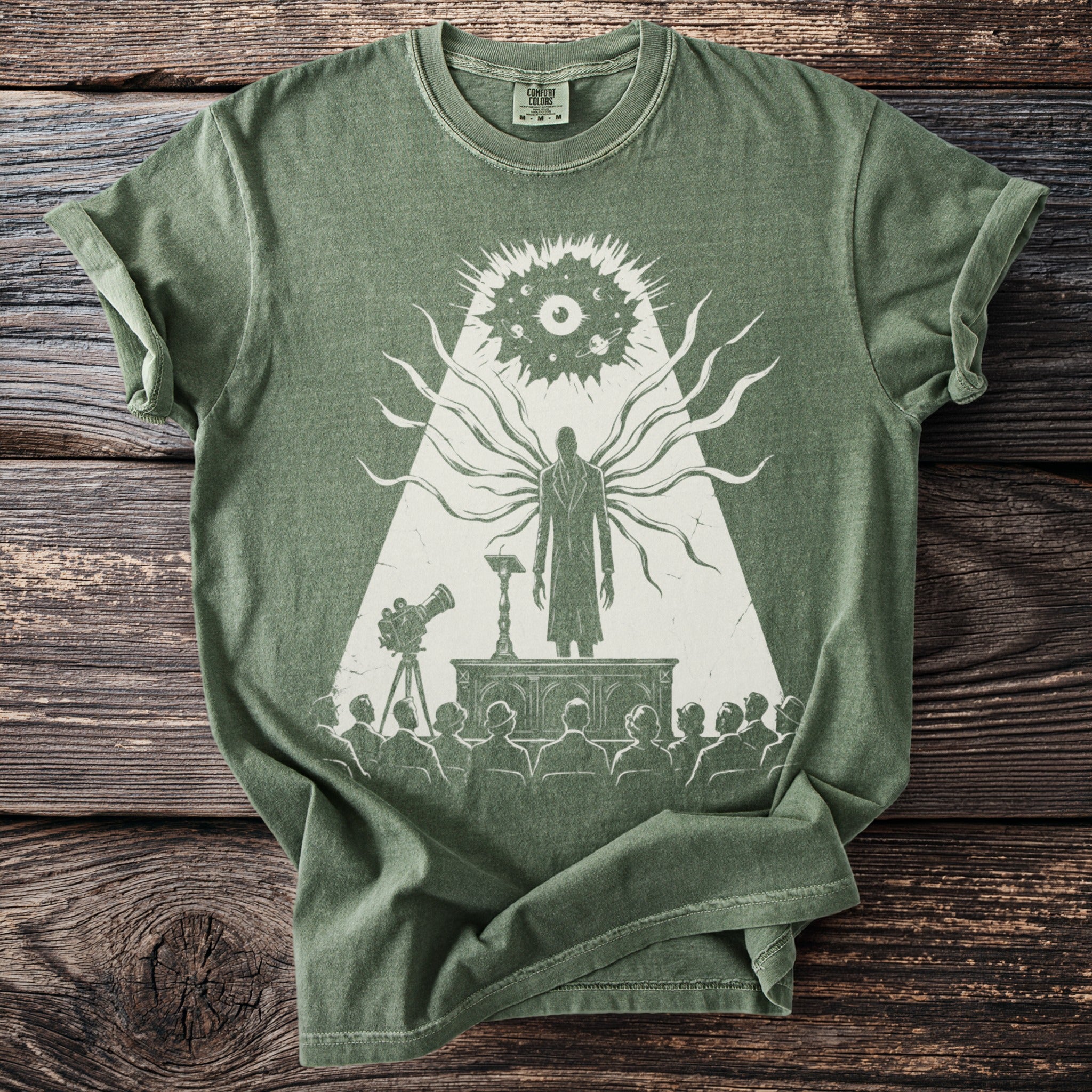 Green t-shirt with graphic of a figure with tentacle-like arms addressing an audience.