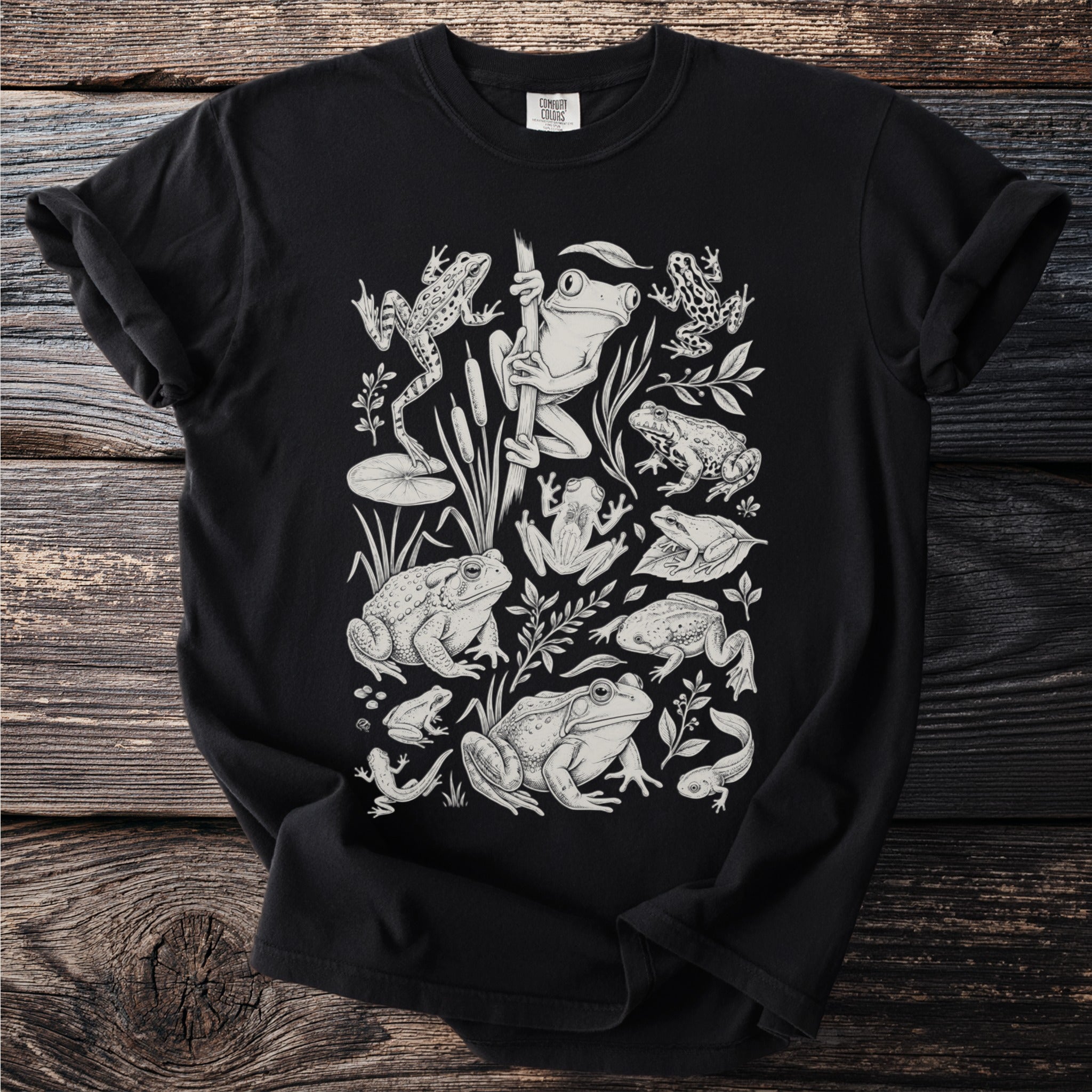 Black t-shirt with white line drawing of various frogs, tadpoles, and aquatic plants.