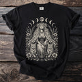 Black t-shirt with a centered illustration of a woman with cats, flowers, and moon phases.