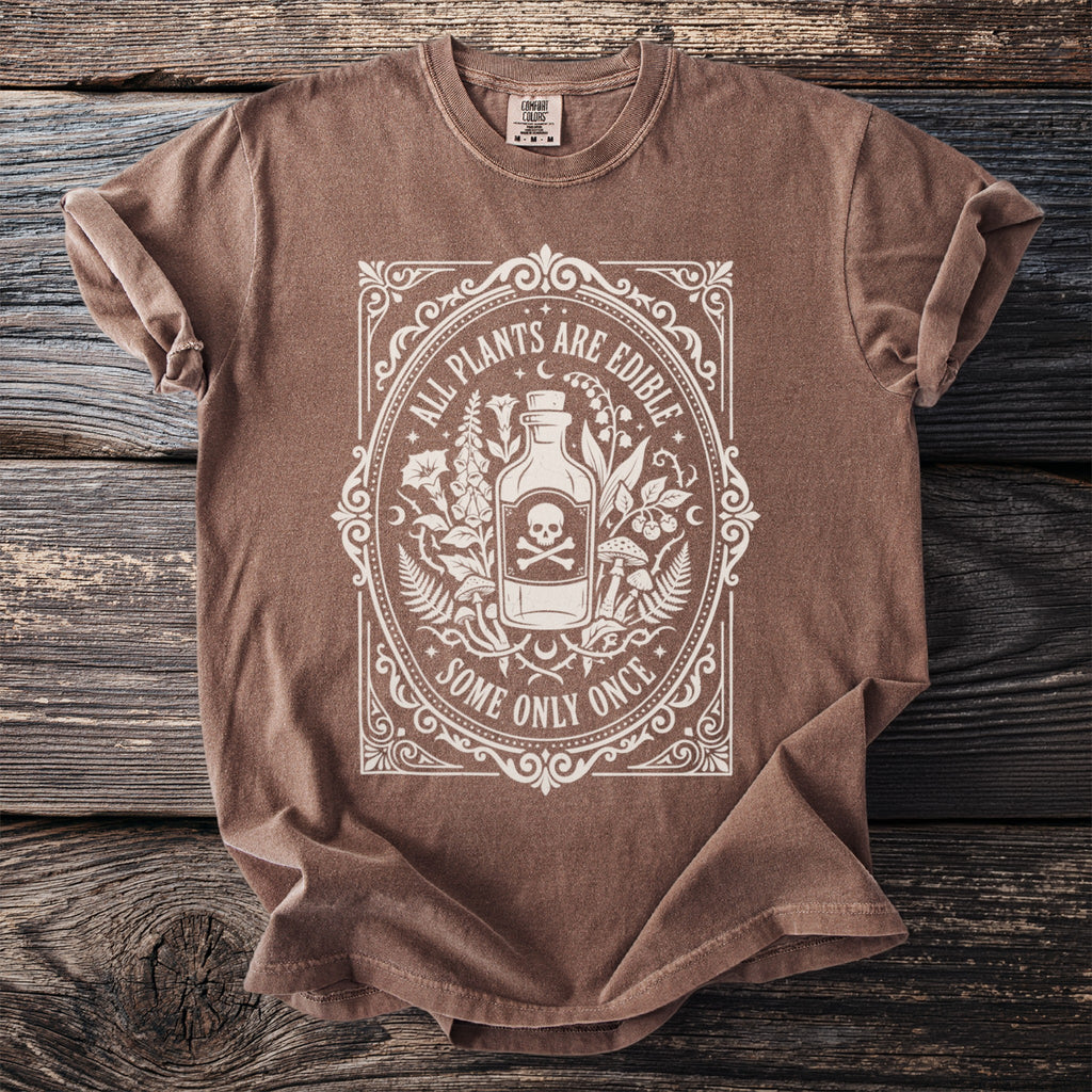 Brown t-shirt with white distressed print of a bottle, skull, and botanical elements.