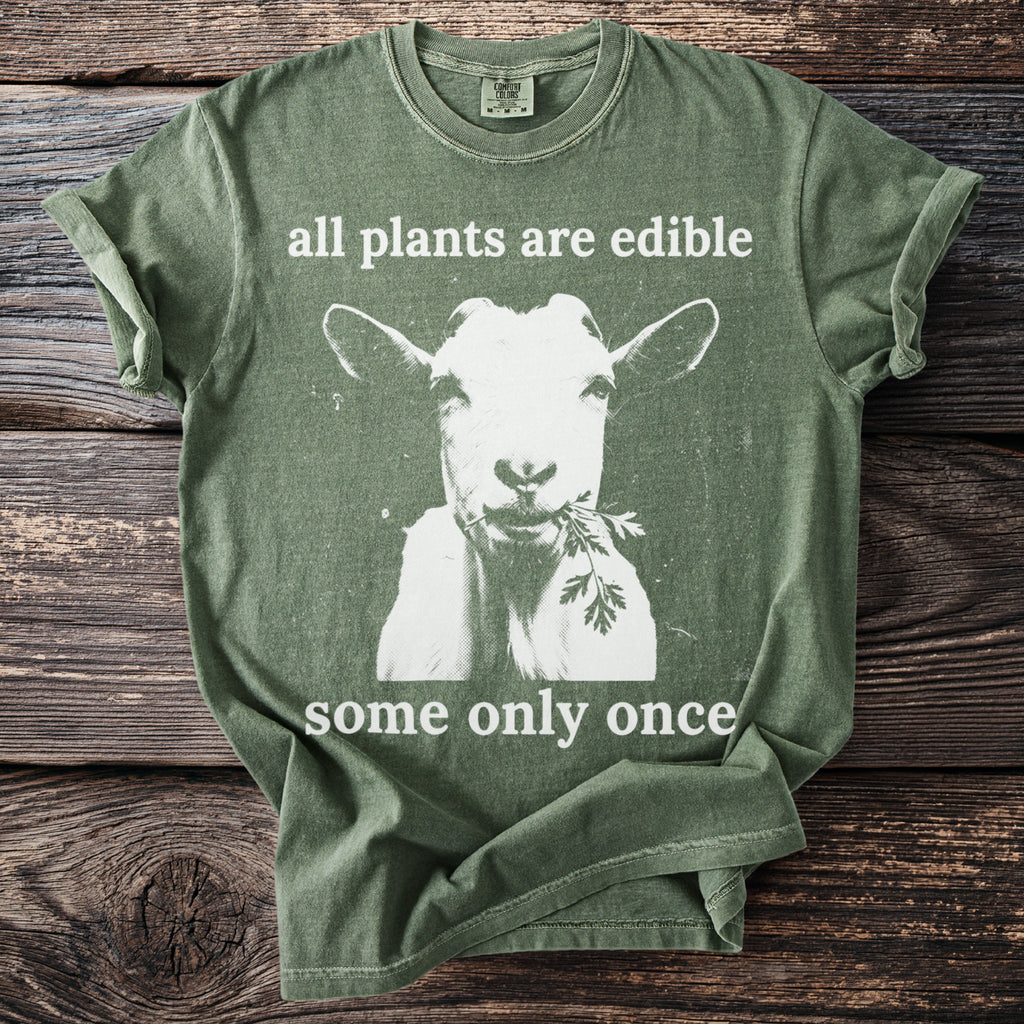 Green t-shirt with goat eating greens and text "all plants are edible some only once".