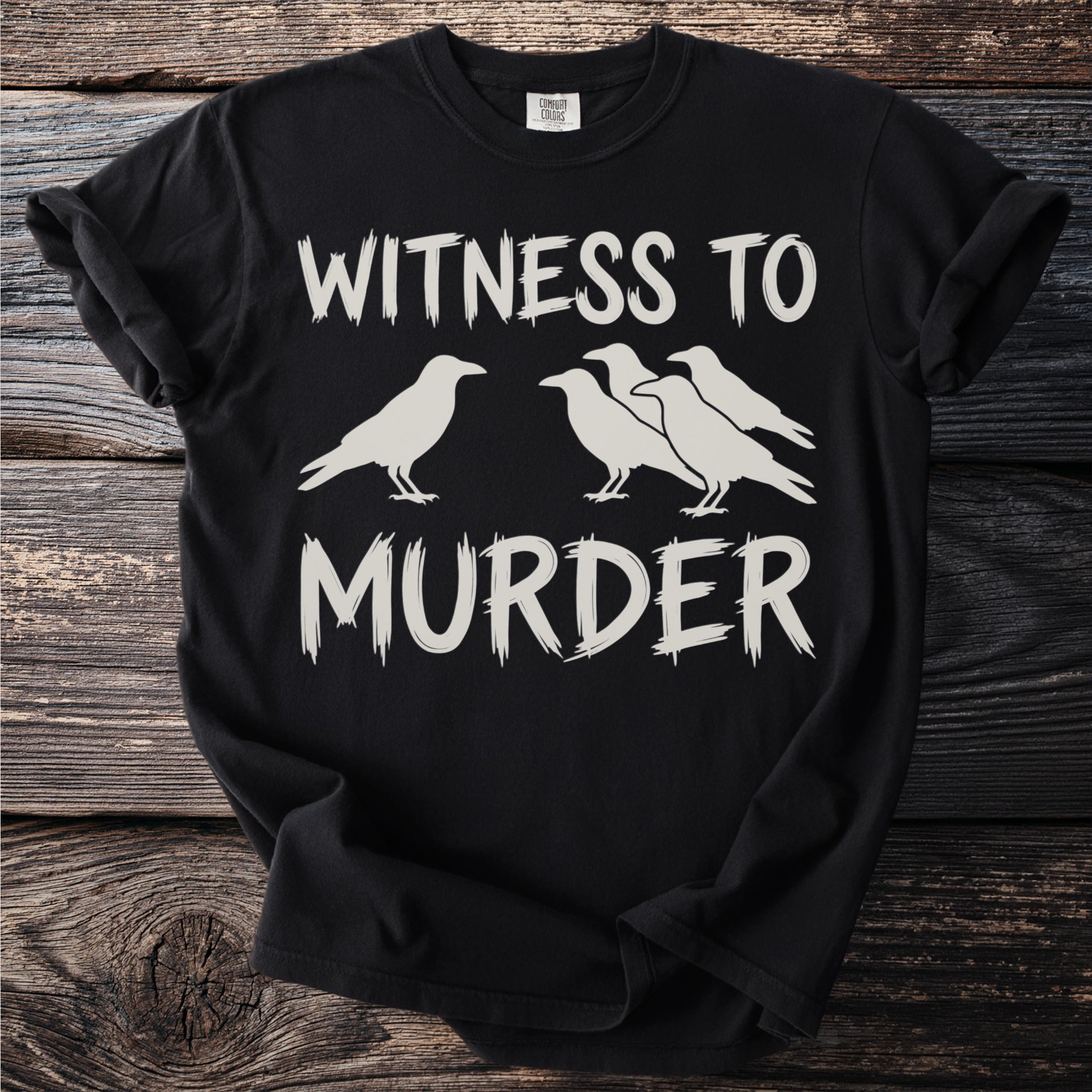 Black Comfort Colors t-shirt with "WITNESS TO MURDER" and crow graphics.