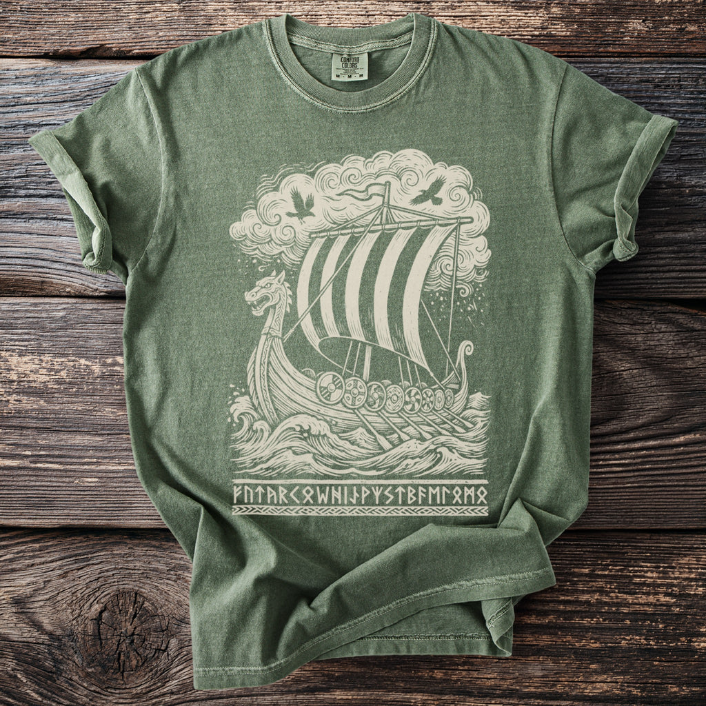 Green t-shirt with a cream graphic of a Viking ship, birds, and runes.