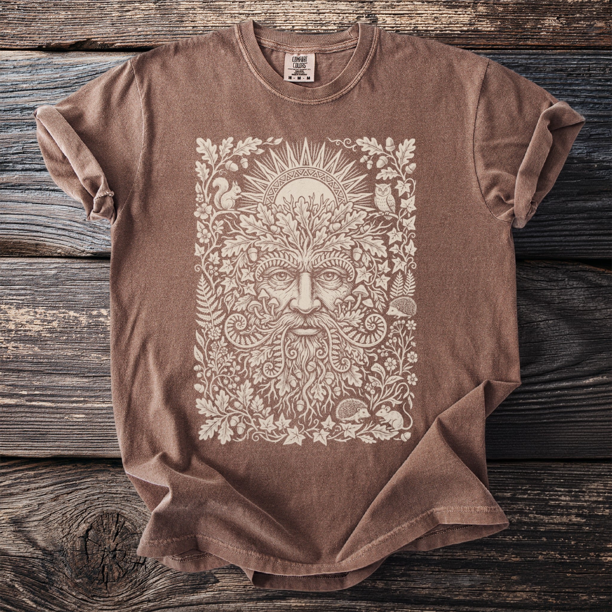 Brown t-shirt with a detailed cream linework design of a Green Man amidst foliage and woodland creatures.